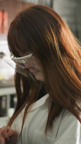 dama con gafas de protección se centra en la tableta mientras lleva a cabo observaciones en el taller de automóviles, el fondo incluye herramientas mecánicas, equipos y espacio de trabajo industrial