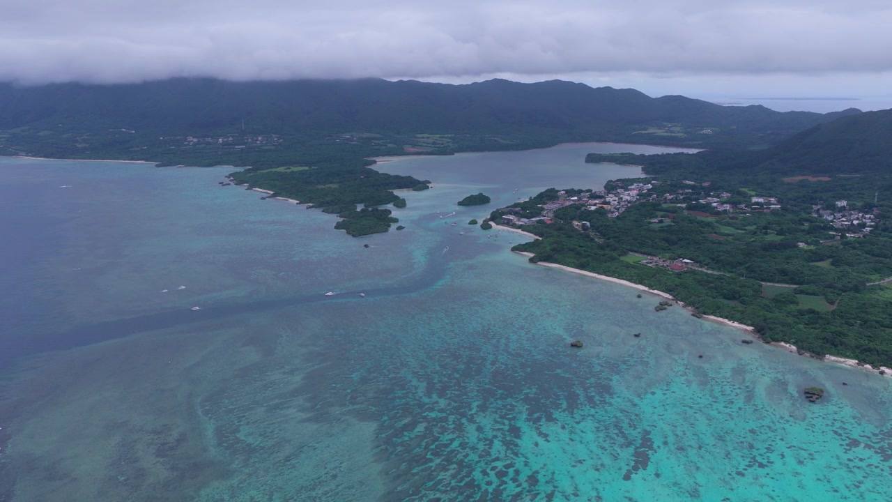 Riprese aeree orizzontali in dolly all'indietro sopra la laguna turchese, le barriere coralline e la costa della spiaggia e baia di Kabira, vicino a Club Med e alla spiaggia di Tabaga, Isola di Ishigaki, Giappone.