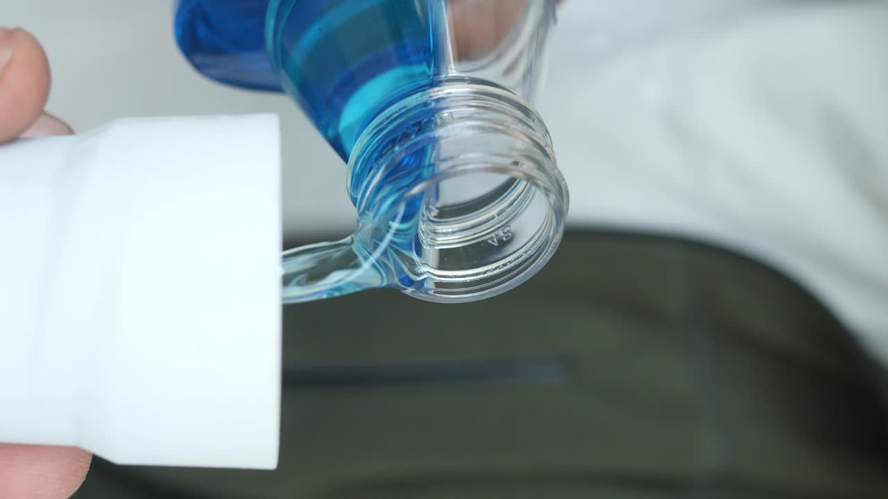 Close-up of blue liquid being poured from a clear bottle