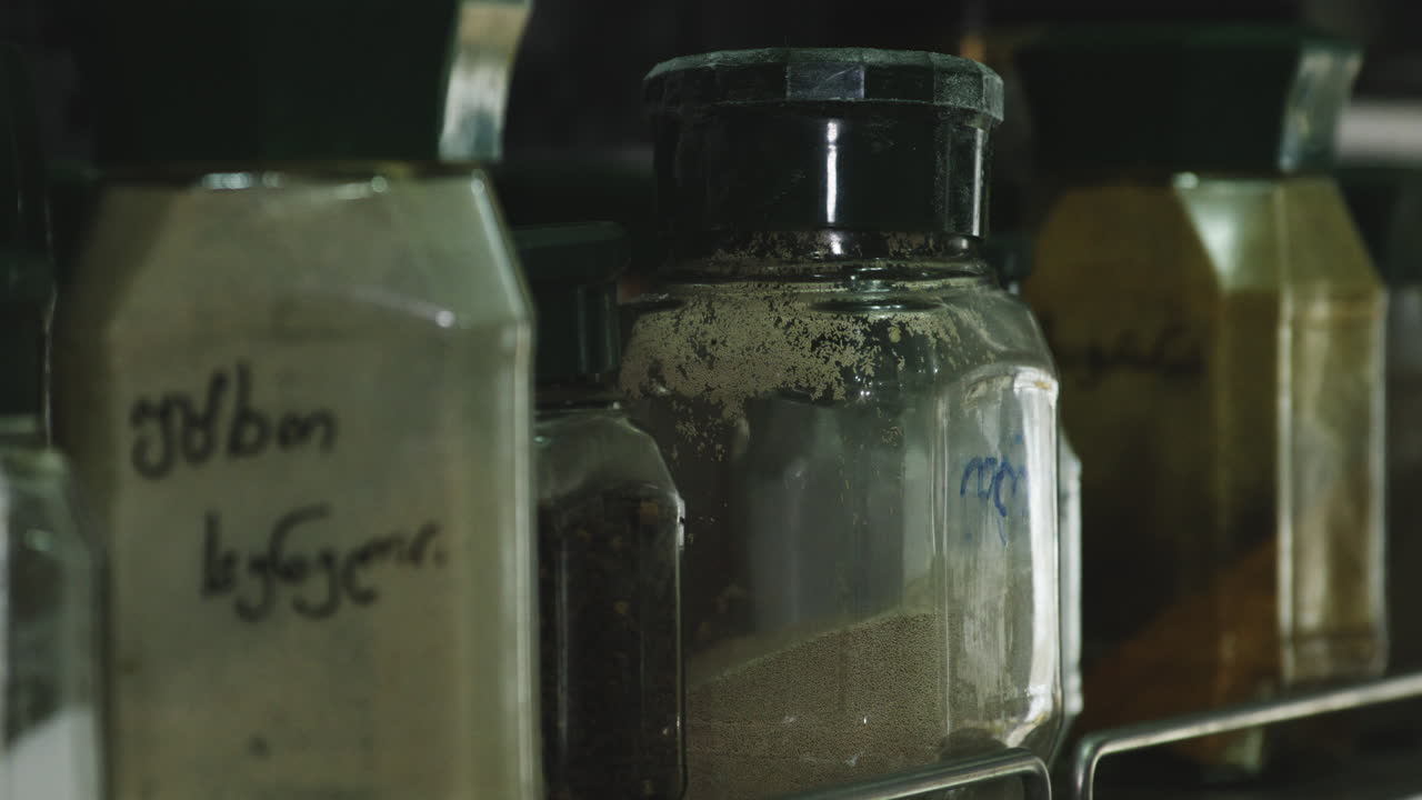 Jars with flour and spices labeled in georgian on kitchen pantry shelf