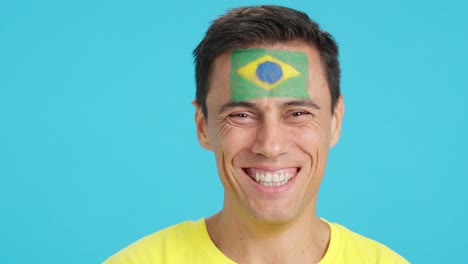 man with a brazilian flag painted on the face smiling