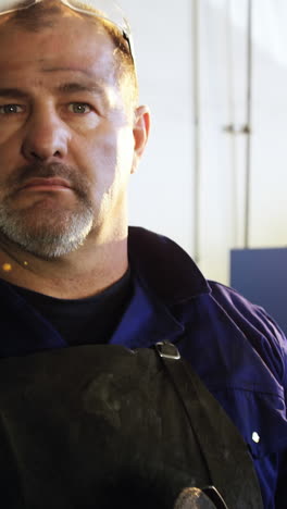 welder holding electric saw in workshop