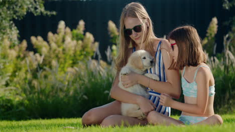 children play with a puppy in the backyard of the house. sitting on the green lawn