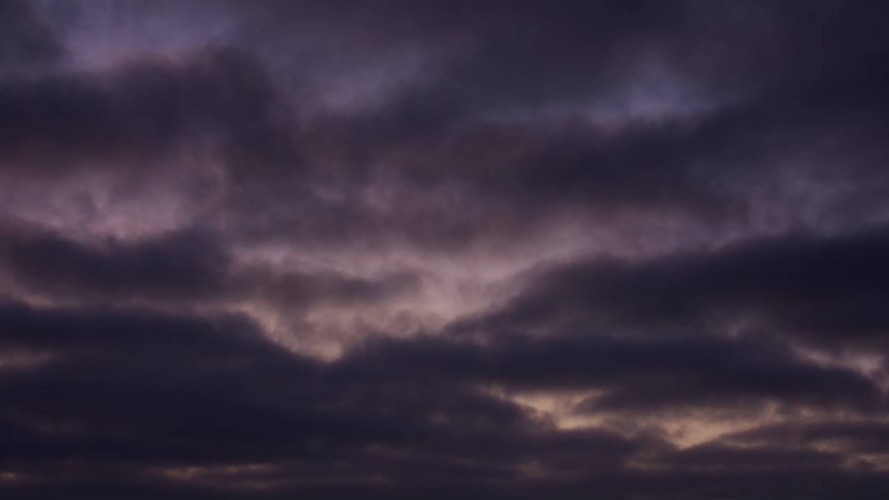 Moody storm clouds forming layered patterns across a dark evening sky, creating a dramatic and atmospheric weather background with natural light and depth