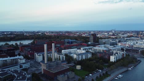 Aerial-flyover-power-plant-smoke-stacks-on-Helsinki-waterfront-at-dusk