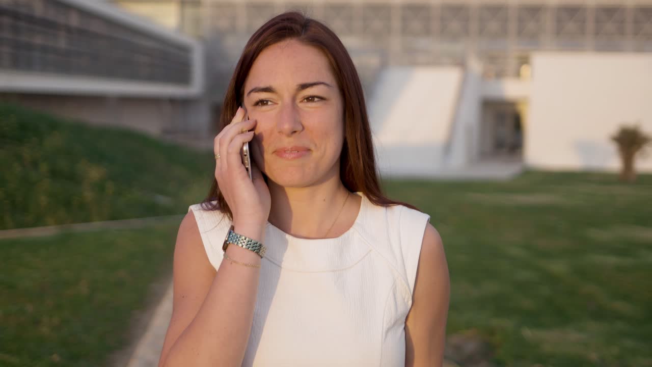 una joven sonriente hablando por teléfono mientras caminaba por la calle.