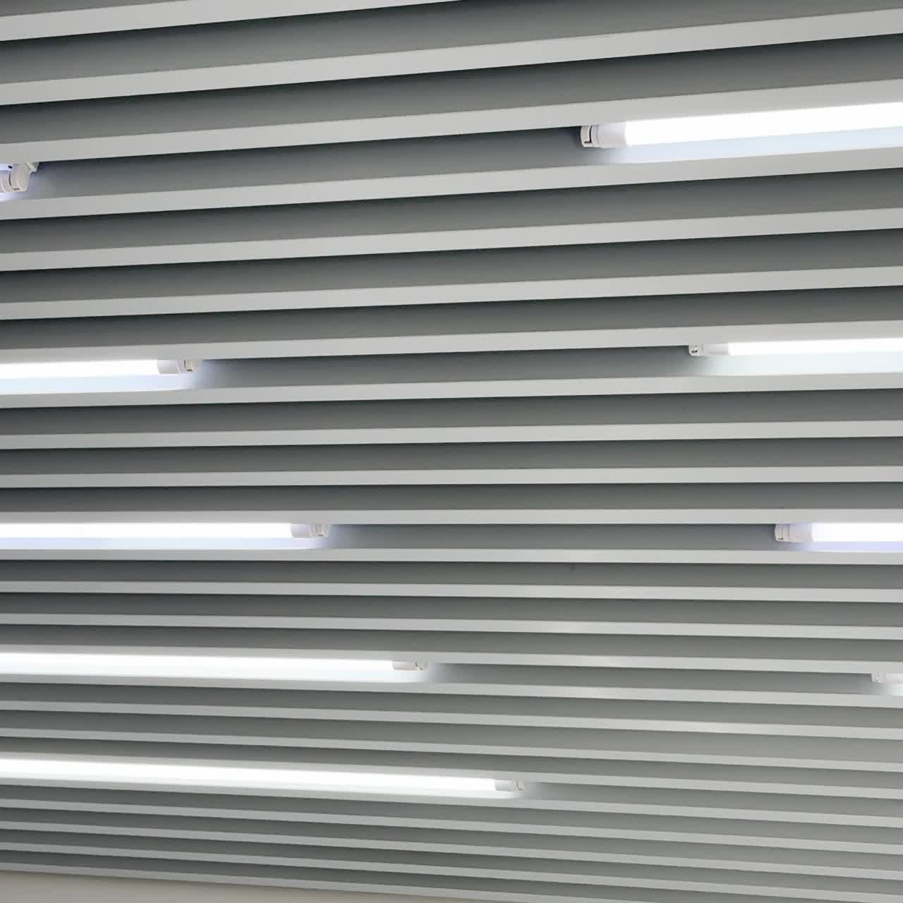 Ceiling decorated with panels in diverse directions and led lamps among them. Black and white image of switched on illumination. Low angle view