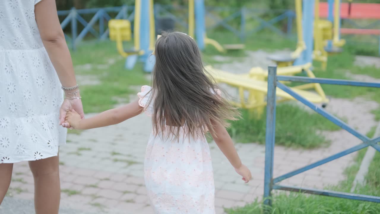 임신 한 어머니 와 어린 딸 은 나무 와 초록색 으로 둘러싸인 공원 의 놀이터 에서 함께 놀이 를 즐긴다