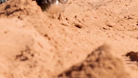 a detailed view of dirt bike tires navigating a sandy trail, showcasing tire tracks and sandy terrain.