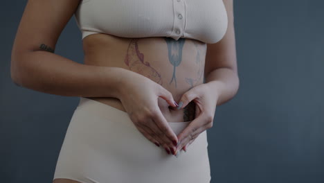 woman with hands forming heart shape on her stomach