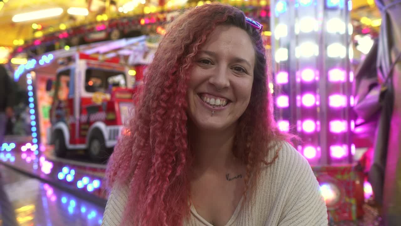 la donna si gira e sorride alla telecamera con la giostra fuori foco dietro di lei