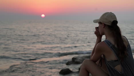 primer plano de una mujer fotografiando el atardecer con su cámara