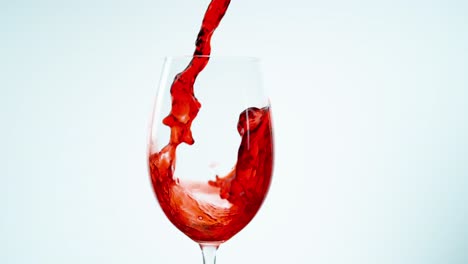 un tiro fijo de vino tinto que se vierte enérgicamente en un gran vaso de vino claro