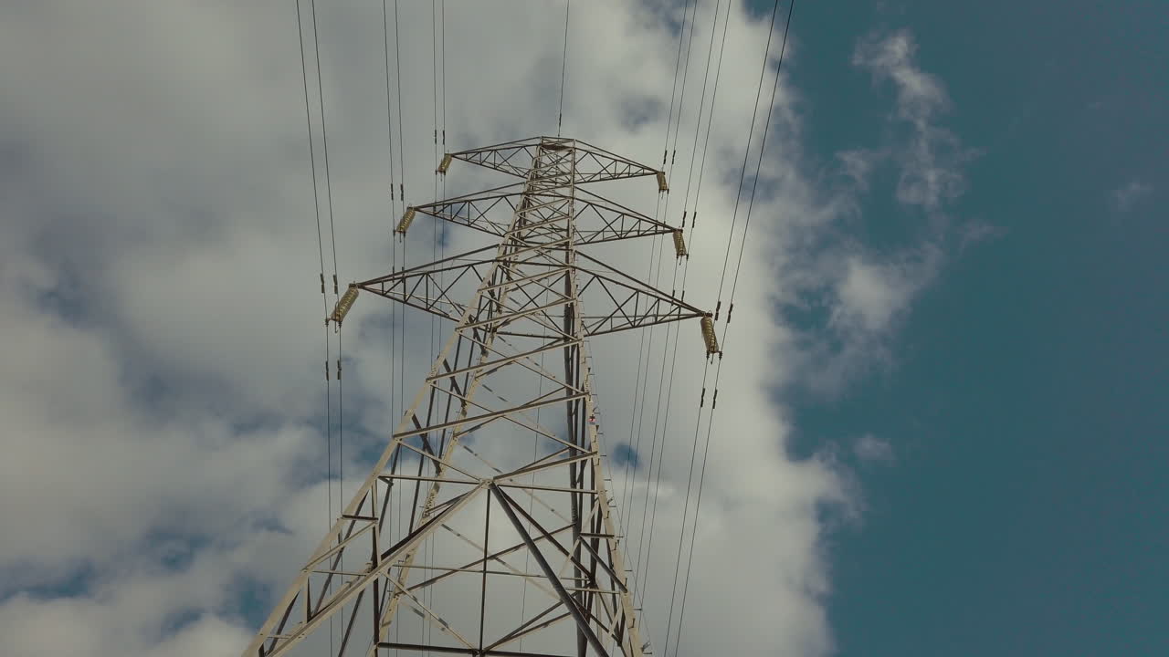 Electricity pylon in the middle of a farmers field with cables stretching across the blue sky of the countryside