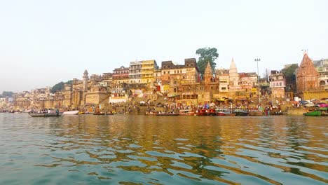 river ganges in varanasi with buildings lit in the morning sunrise in india