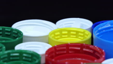 Closeup-of-Used-caps-from-used-plastic-bottles-with-different-colors-that-turn-in-front-of-a-black-background