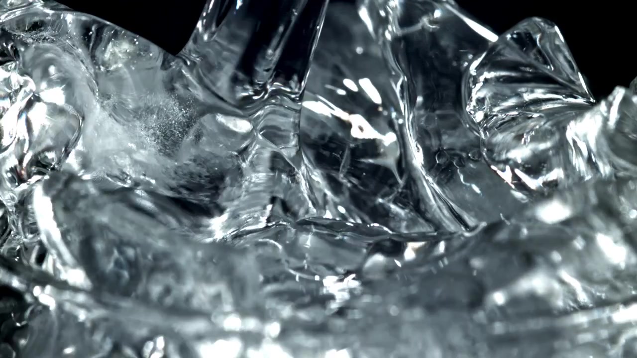 Acqua che si versa al rallentatore su cubetti di ghiaccio trasparenti