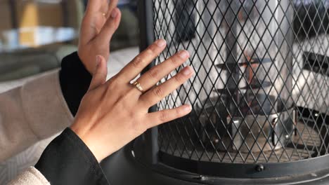 woman warms hands by outdoor heater