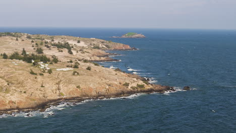 rocky-coastline-with-strong-winds-and-waves-from-the-sea-in-thailand,-aerial-dolly-in