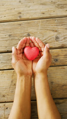 video vertical de primer plano de corazón y manos en fondo de madera
