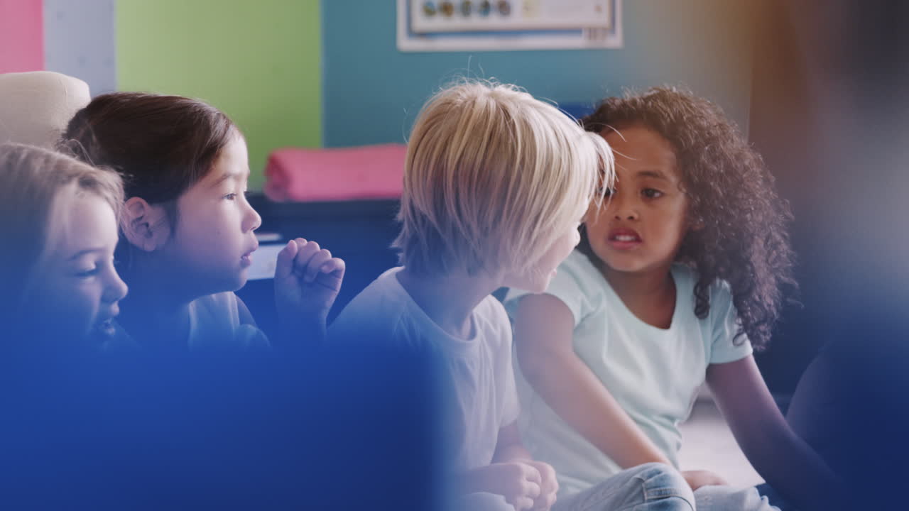 Group Of Elementary School Pupils Sitting On Floor Talking To Each Other