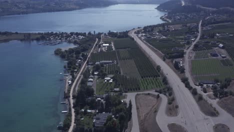 4k aerial super high altitude over looking cottage country beach homes parallel fly over lakeside docks quiet suburb across wine hemp marijuana farms roadway exit entrance into the main highway 1-2