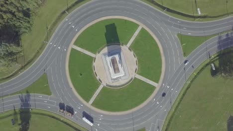 la cámara del dron gira alrededor de un anillo circular de tráfico en una avenida de la ciudad.