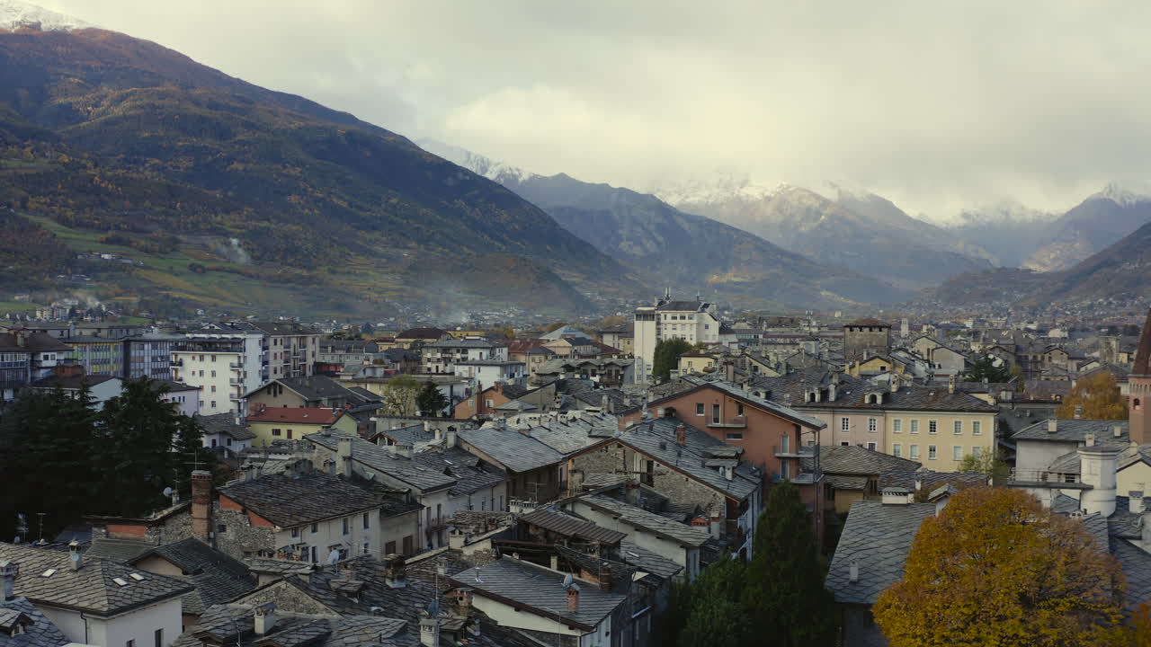 Una vista maestosa della Valle d'Aosta, Italia, con imponenti montagne innevate e tetti, ripresa da drone.