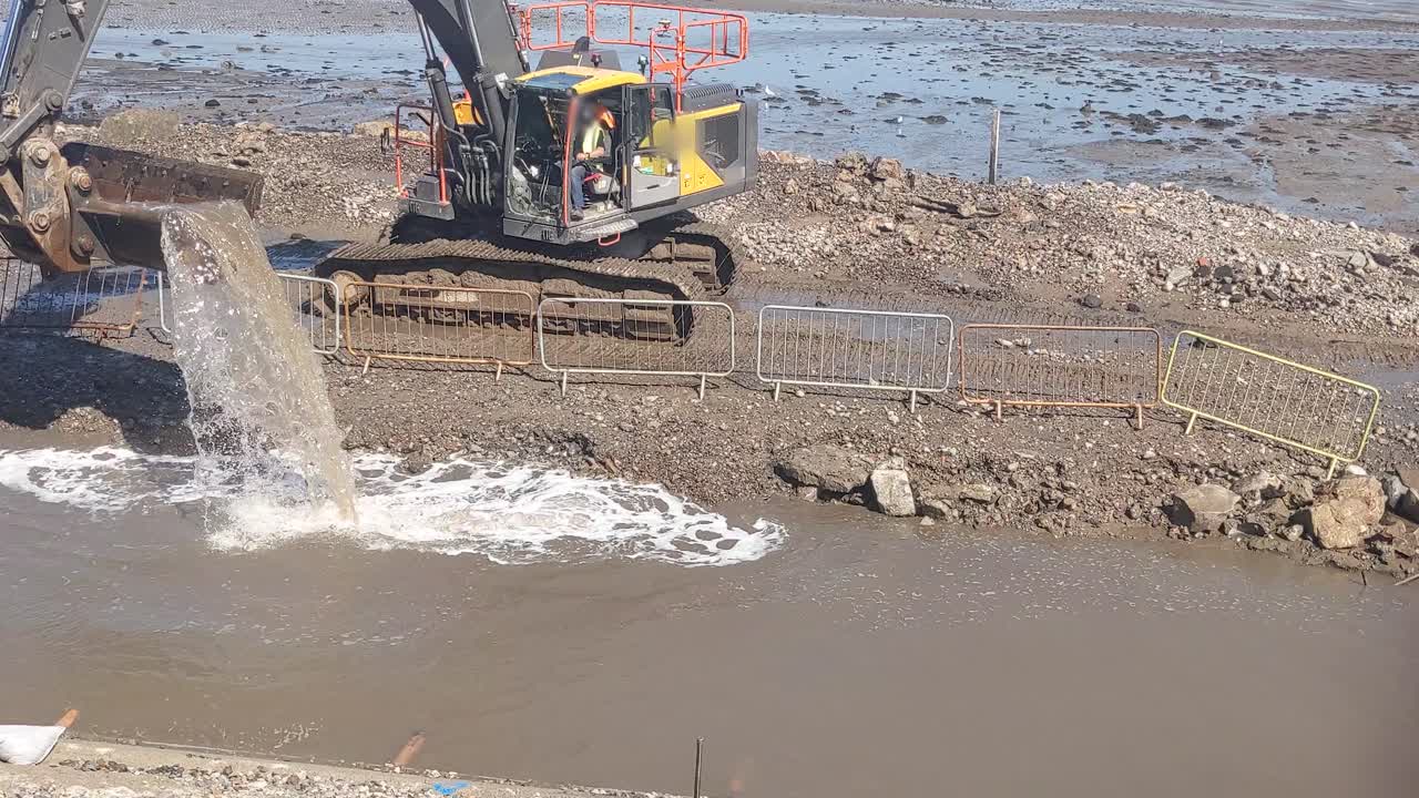 excavador que elimina el agua para trabajos esenciales en el puerto costero