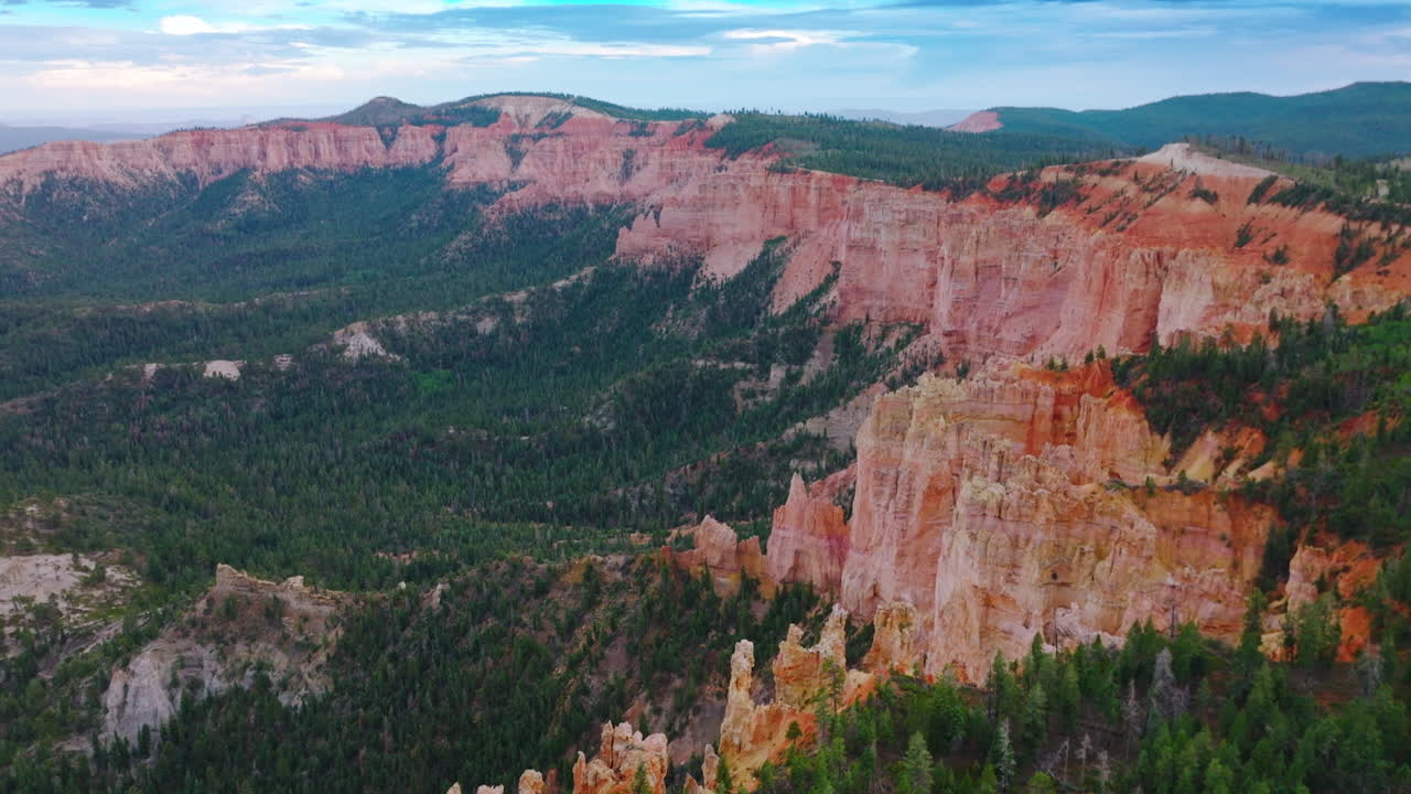 Sheer cliffs of wonderful canyons rising over the pine tree woods. Blue skies with clouds at backdrop. Aerial view.