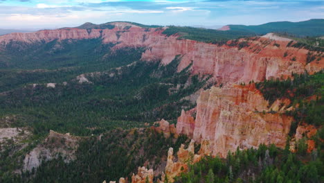sheer cliffs of wonderful canyons rising over the pine tree woods. blue skies with clouds at backdrop. aerial view.