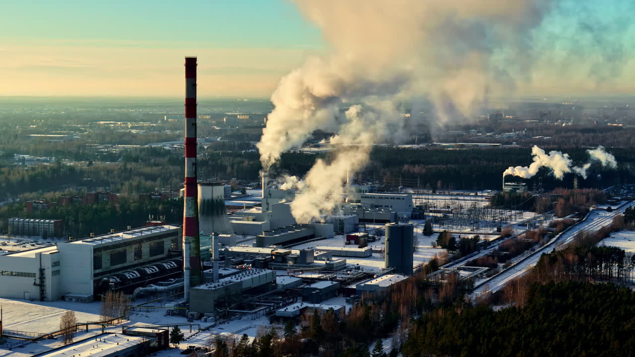 Stabilimento industriale con ciminiere che rilasciano vapore su un paesaggio innevato vicino a Cēsis. Cesis, Lettonia