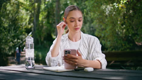 спокойная женщина с наушниками, сидящая за столом в парке. девушка слушает подкаст.