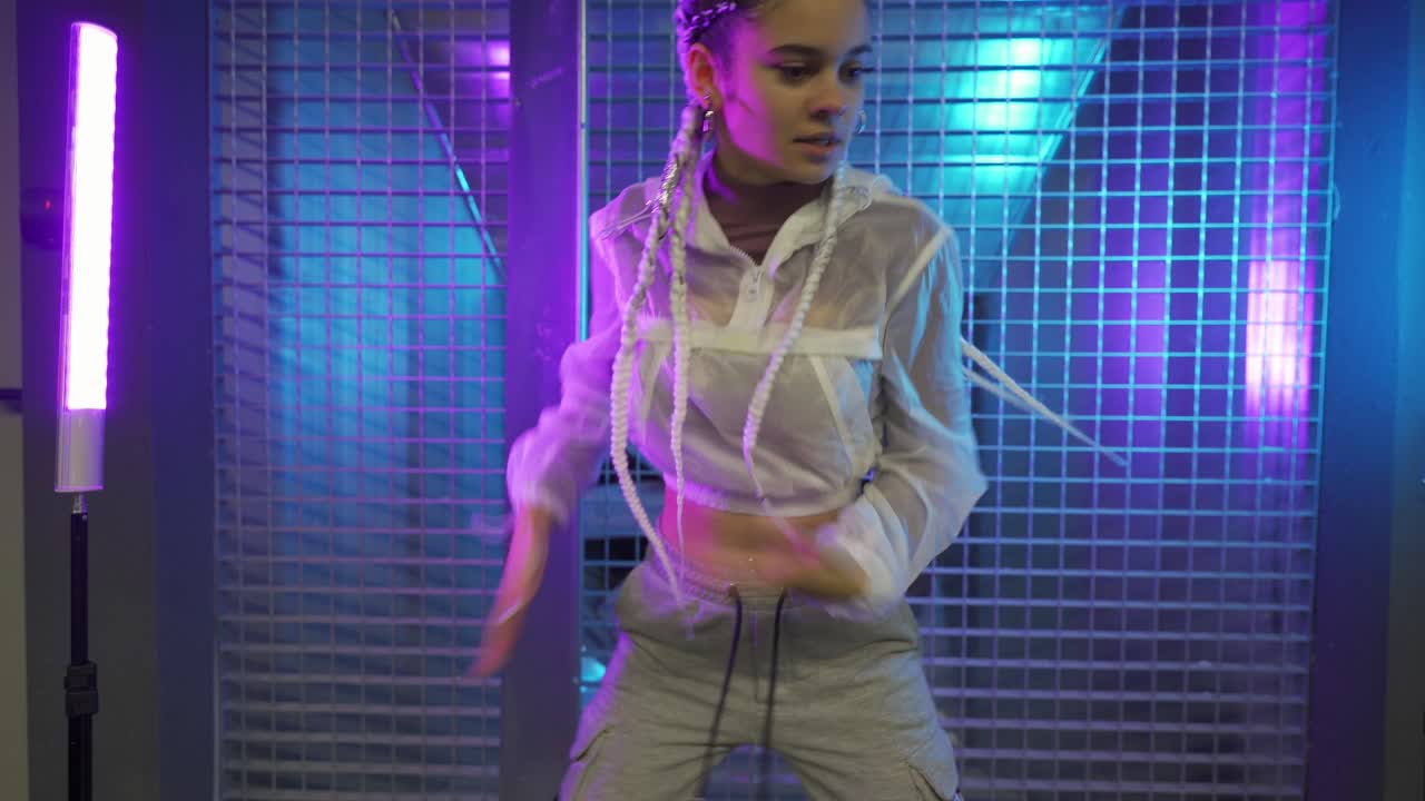Donna con trecce che balla davanti a luci al neon