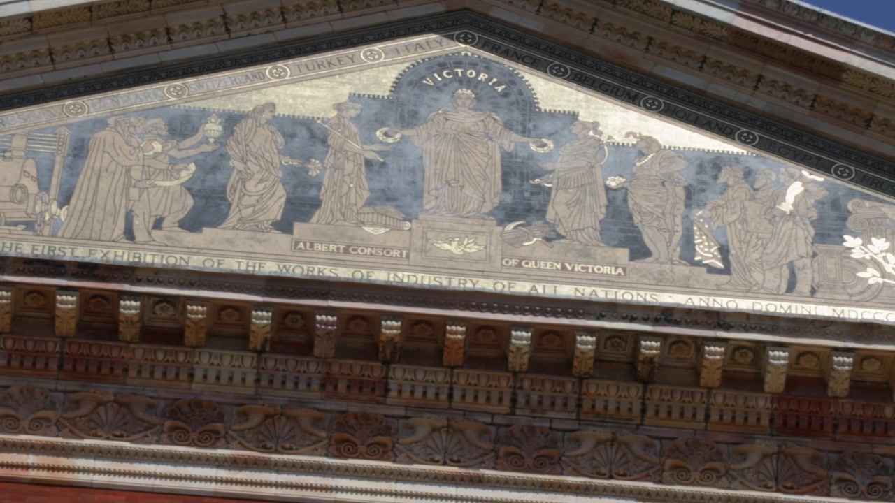 Solbeskinnet nærbillede panorerer hen over udskåret fronton med klassiske figurer på museumsfacaden