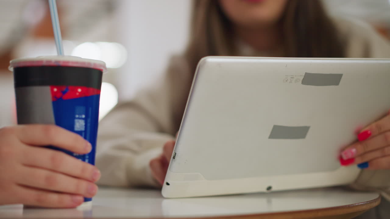 Young blonde lady in black jacket interacts with friend during conversation at bright indoor space, showing expression of focus and casual connection