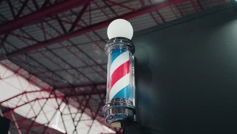 barber shop pole with spinning stripes and lighted top against industrial backdrop