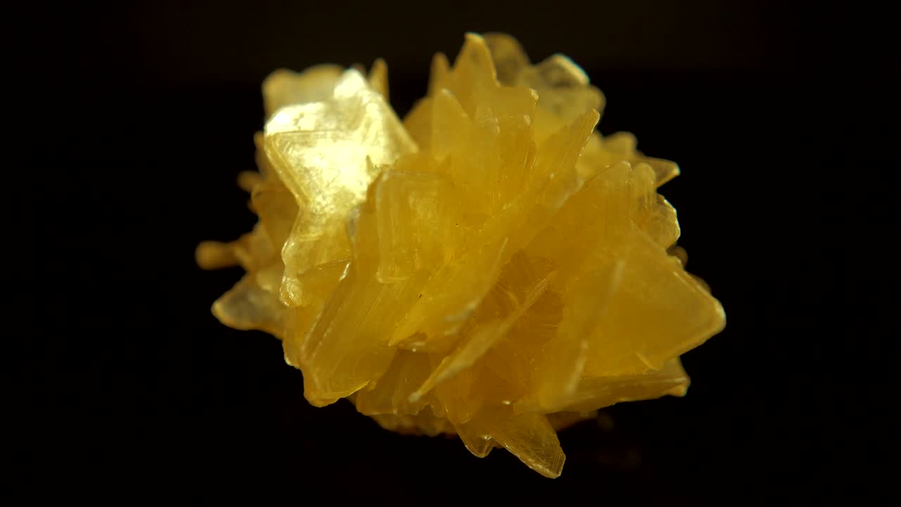 검은색 배경 앞에 노란색 미네랄 (바리트) 을 원활하게 회전시니다.
