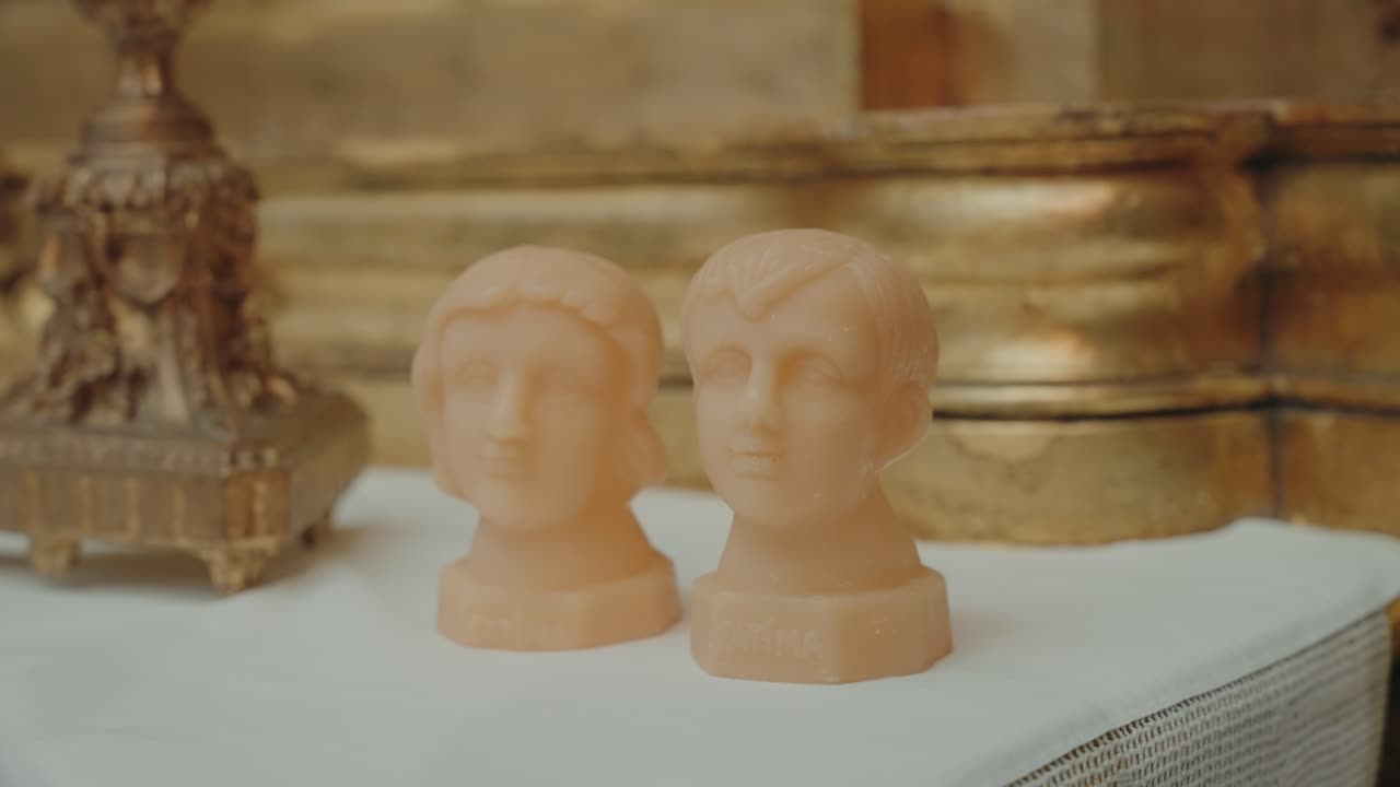 Close view of two small sculpted head figures placed on a decorated church table
