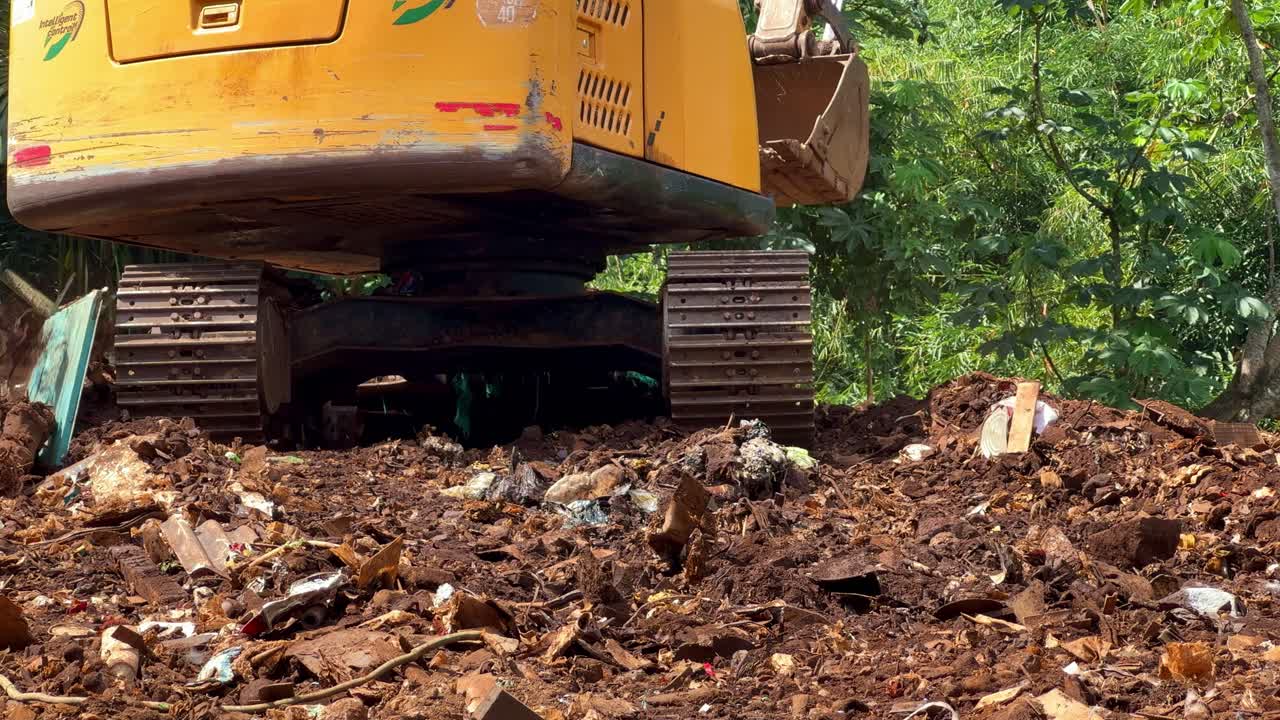 Excavator metal tracks rolling over soil and debris