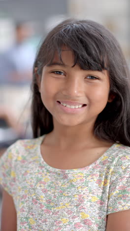 vertical video: in school, young biracial girl with long dark hair is smiling