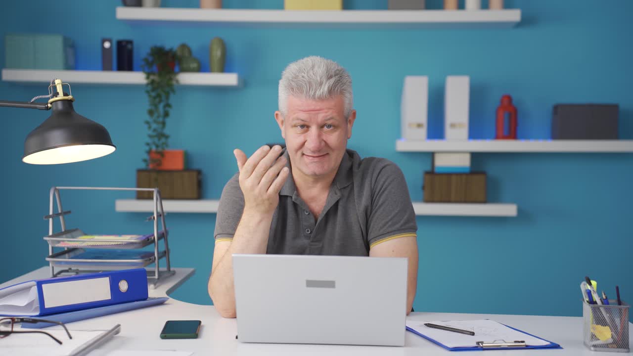 홈 오피스 워커 남자가 카메라 앞에 와서 당신을 부르고 있습니다.