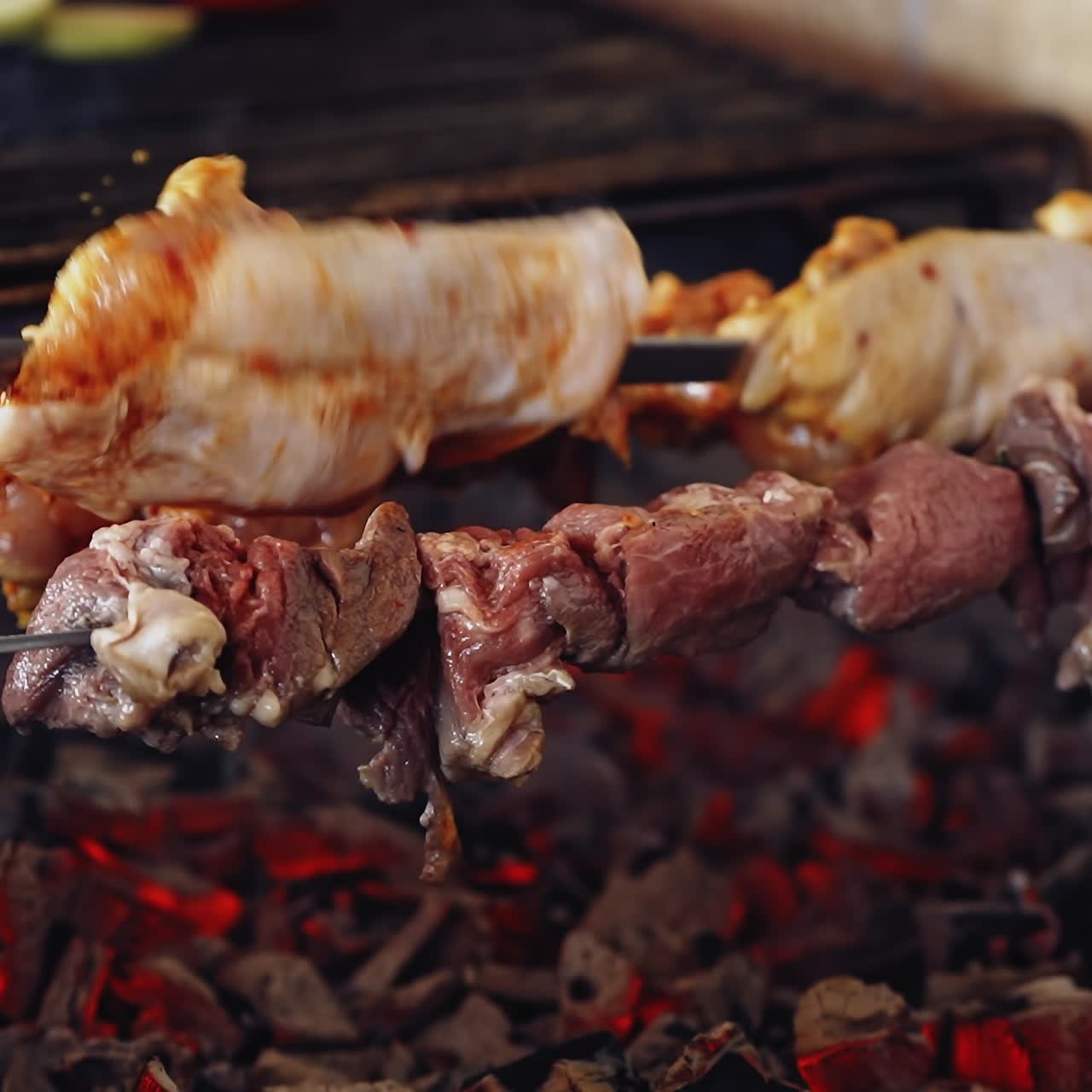 Meat cooking on charcoal. Delicious barbeque on metal skewers. Process of frying juicy meat. Close-up.