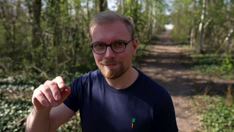 happy, confident caucasian man takes of his glasses, medium shot, outside in nature