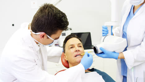 dentista examinando a un paciente masculino con una herramienta