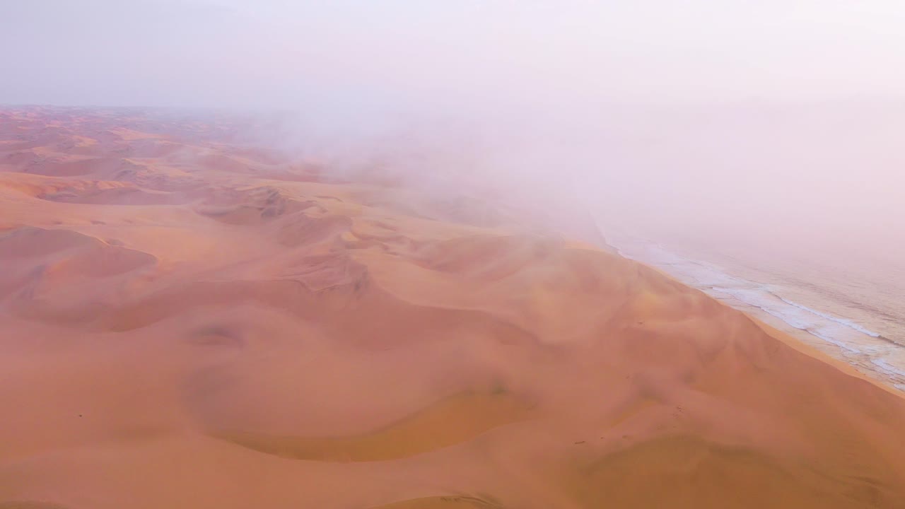 Una bellissima ripresa aerea dall'alto attraverso nuvole e nebbia sopra le vaste dune di sabbia del deserto del Namib lungo la Costa degli Scheletri in Namibia 1