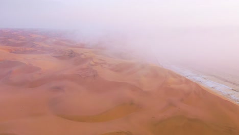 Gute-Hohe-Luftaufnahme-Durch-Wolken-Und-Nebel-über-Den-Weiten-Sanddünen-Der-Namibwüste-Entlang-Der-Skelettküste-Namibias-1