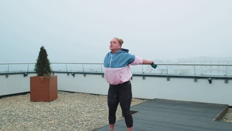chica deportiva en ropa deportiva hace yoga estiramiento ejercicio usando banda de goma en el techo de la casa al aire libre