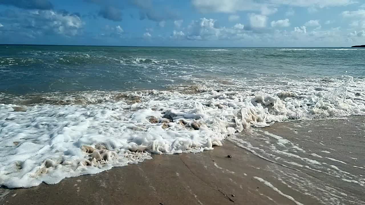 las olas del océano en cámara lenta salpican sobre la pintoresca playa de arena de la isla el cielo azul relajante la tranquila costa