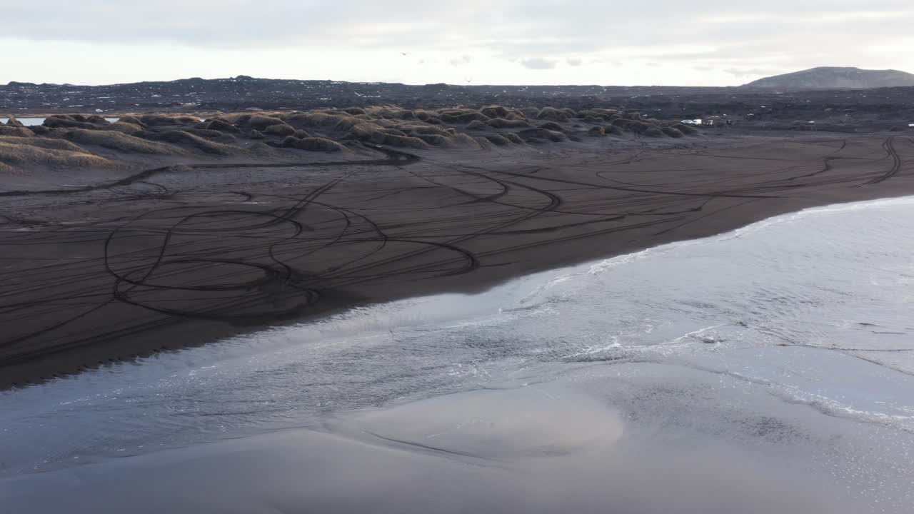 marea baja en la playa volcánica negra de sandvik en islandia, reflejo del cielo en la arena mojada, antena
